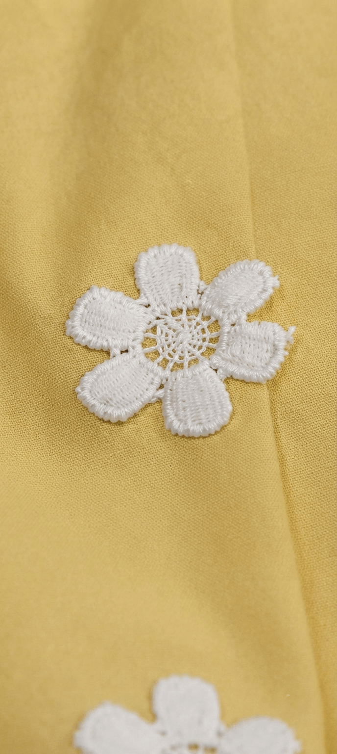Close-up of hand embroidered white daisy motifs on yellow cotton lawn kurta